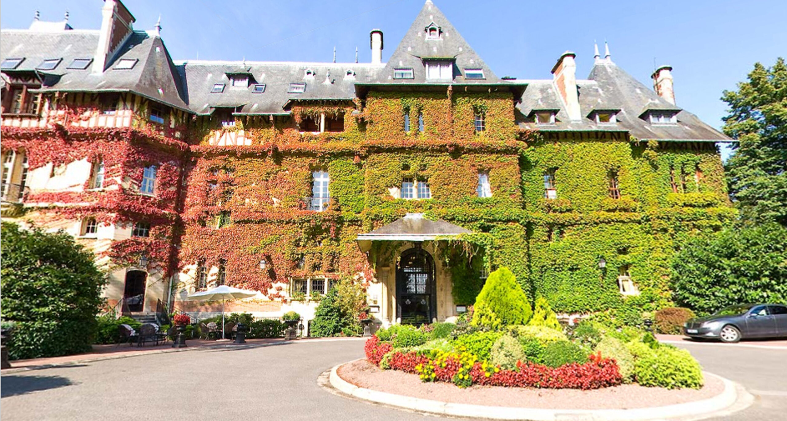 a building with a large green wall and a circular driveway. Primavera em Chantilly