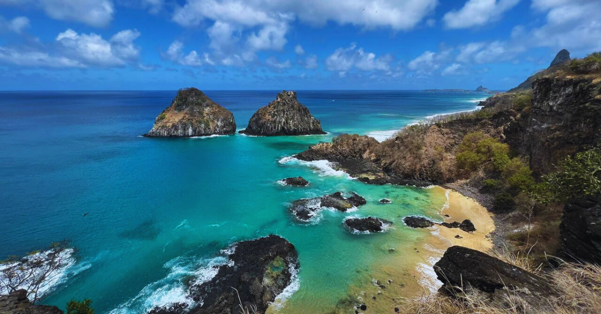 Paisagem paradisíaca com mar azul e falésias, cenário de eventos em Fernando de Noronha.
