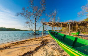 Barcos coloridos ancorados na margem da Lagoa do Portinho em Luís Correia, Piauí, com dunas ao fundo.