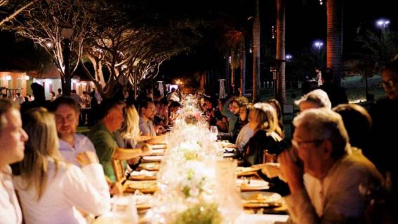 Mesa longa com 100 convidados em área externa da pousada Suíça Mineira em Monte Verde, Minas Gerais, durante evento gastronômico.